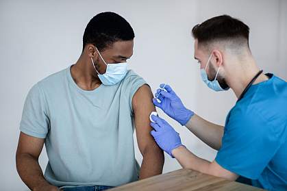 Black man with face mask getting immunized