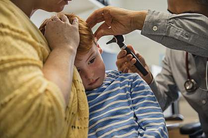 Boy’s ear being examined by a doctor with an otoscope