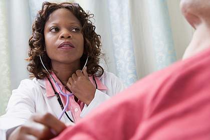 Doctor listening to patient in hospital bed with stethoscope