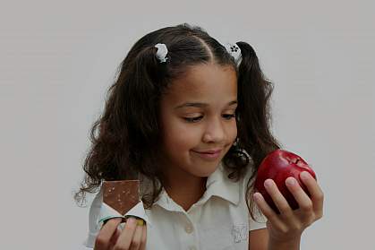 A girl deciding what to eat, with chocolate in one hand and an apple in the other.