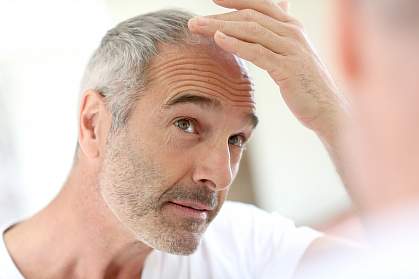 Older man looking at his hair in a mirror