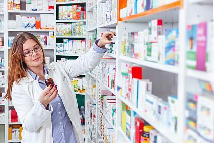Woman pharmacist taking prescription drugs from shelf