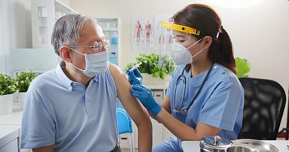 Nurse giving vaccination to senior person