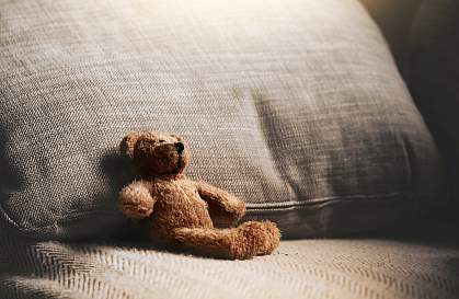 Teddy bear sitting alone on couch