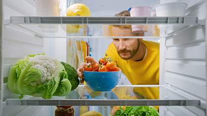 Man taking bowl of tomatoes from refrigerator