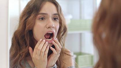 Woman checking the inside of her mouth in a mirror