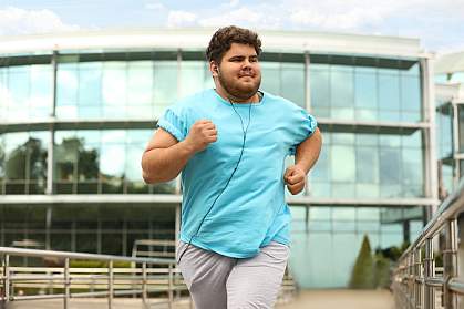 Young man with excess weight running outdoors