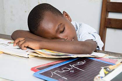 Boy asleep at a desk with his head on a book