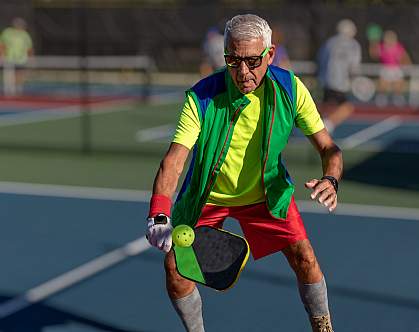 Senior man hitting a pickleball with paddle