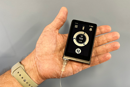 Hand holding a device that looks like a small smartphone
