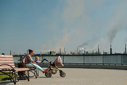 Woman with baby sitting on a bench in a polluted city