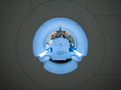 View through an fMRI scanner as three researchers peer inside.