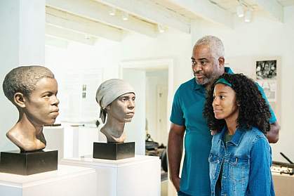 People looking at forensic facial reconstructions of two enslaved African American workers.