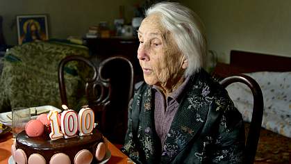 Woman blowing out one hundred candle on her birthday cake.
