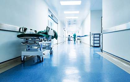Medical worker blurred in the distance down an otherwise deserted hospital hallway.