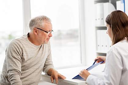 Doctor showing something on a clipboard to a senior man.