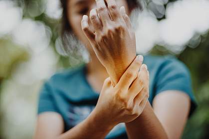 Close up of a young woman holding her wrist in pain or discomfort.