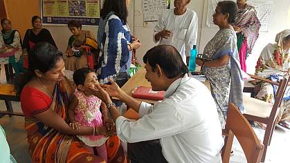 Child sits in mother’s lap during an examination in an Indian clinic.