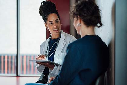 Doctor with a tablet speaking to a hospital patient.