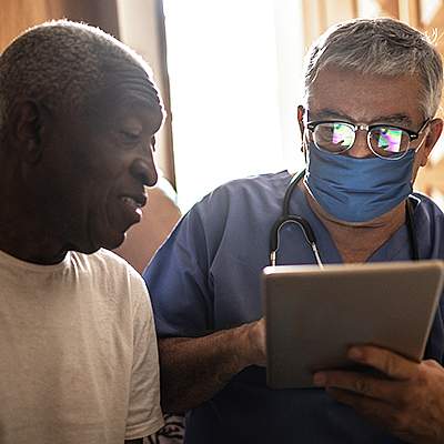 Doctor entering data into a tablet while talking with a patient