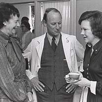 Two women speaking with a man in a lab coat