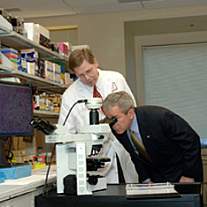 President George W. Bush looking into a microscope.