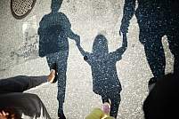 两个成年人走在人行横道上，手牵着手，中间夹着一个小孩。