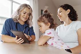 Image of a toddler and two women using a tablet