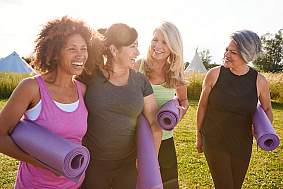 Image of women laughing and holding yoga mats