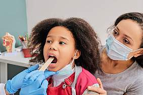 image of a young girl receiving a tonsil exam.