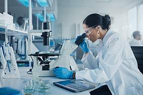Image of a researcher looking into a microscope in a scientific lab