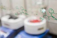 Chemical structures drawn on a glass pane in front of lab equipment