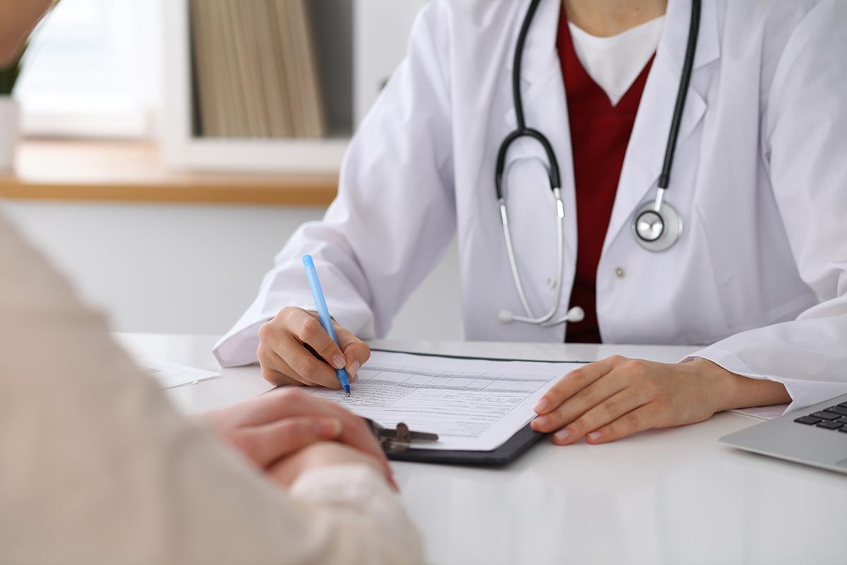 Health care provider completing a form while consulting with a patient