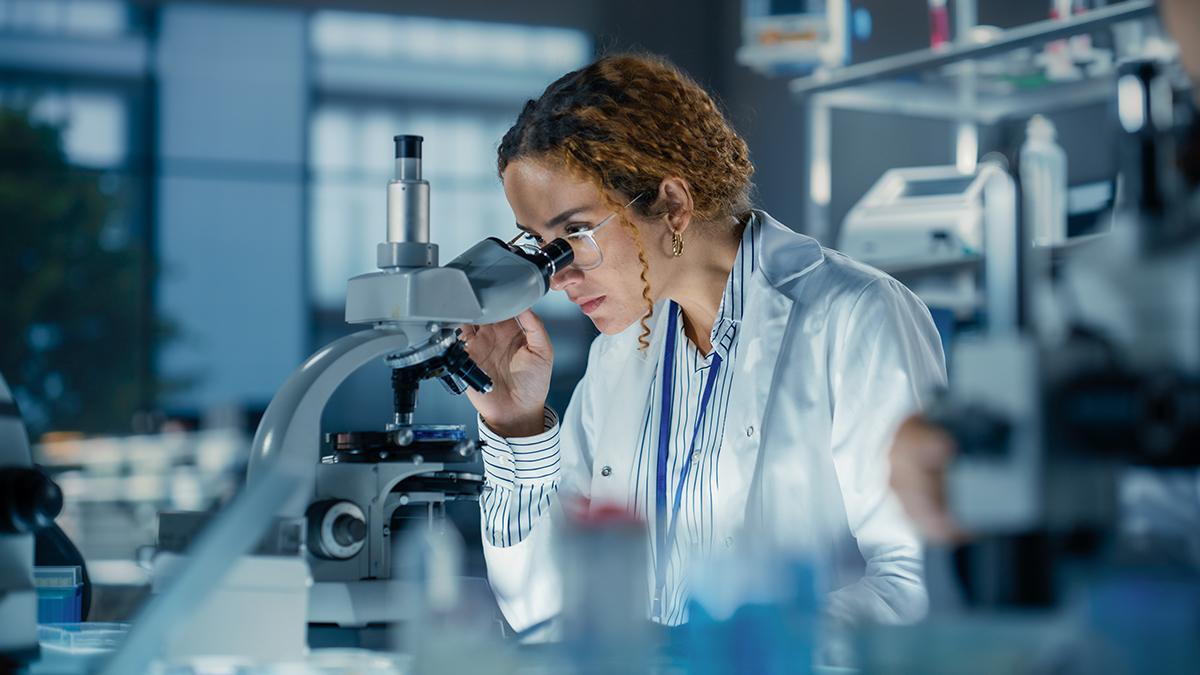 medical research scientist looking at biological samples under a microscope