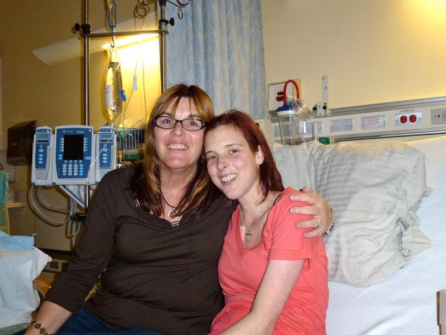 Weller and her daughter, sitting on a hospital bed, smile for the camera