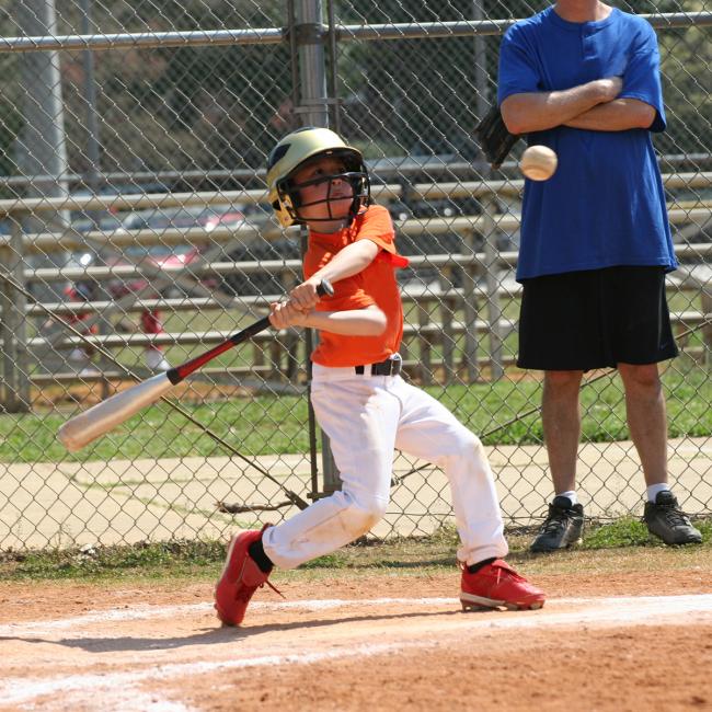 Little League batter hitting the ball