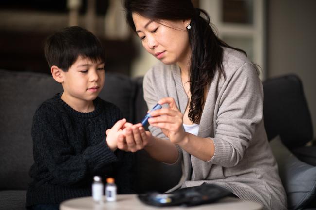 20190618-diabetes.jpg Mother helping son check blood sugar level