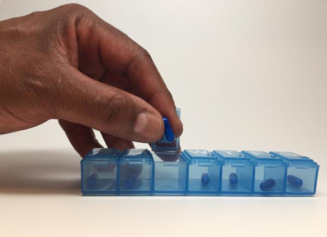 Image of a hand and a pill box.