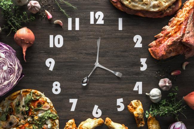 20221101-food-timing.jpg Black wooden clock with utensils as hands and surrounded by food