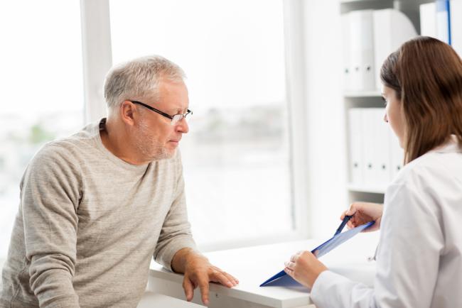 20240206-prostate.jpg Doctor showing something on a clipboard to a senior man.