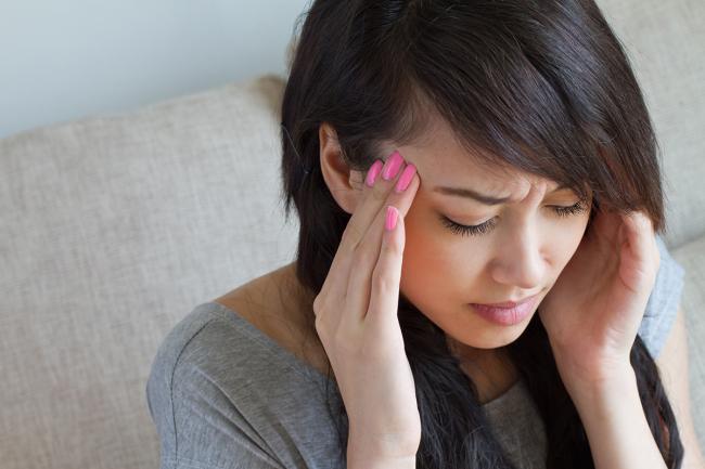 20240730-headache.jpg Woman holding her head in pain.