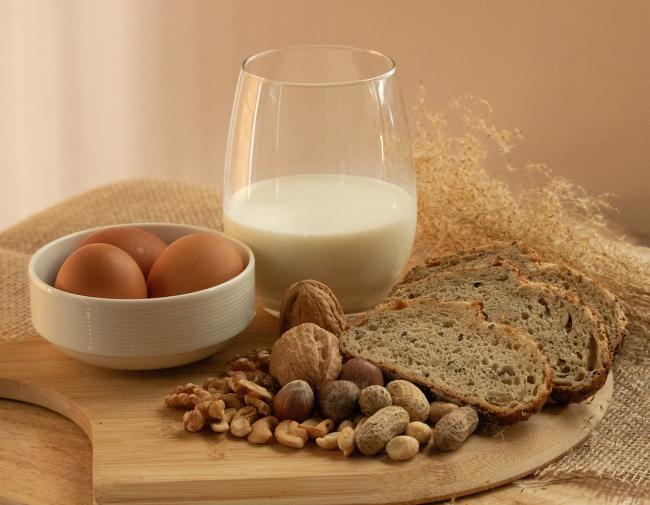 Peanuts, milk, eggs, wheat, cashews, walnuts, and hazelnuts on a wooden tray.