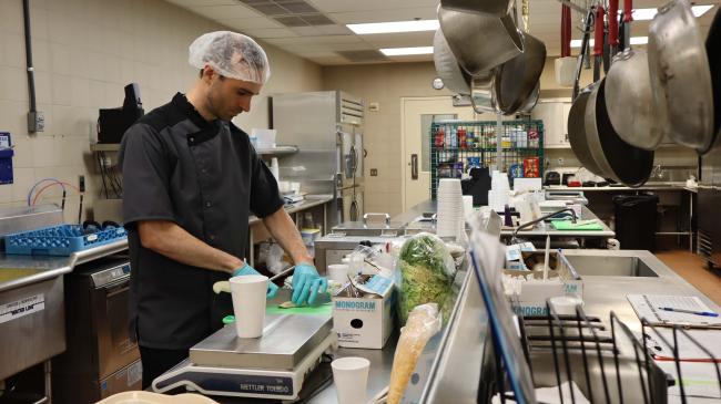 A man chops vegetables in a hospital kitchen.