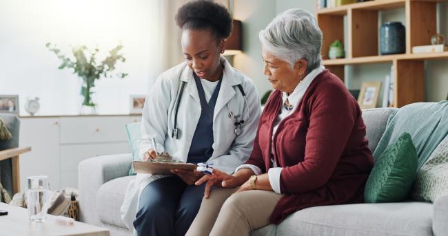 Elderly Latina woman speaking to a young Black woman doctor