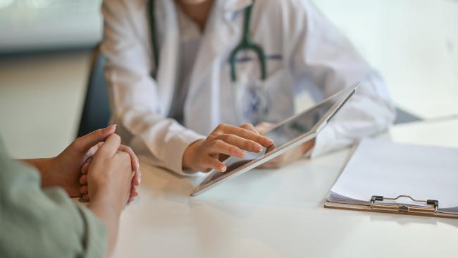 Image of a doctor showing a patient something on a tablet screen.