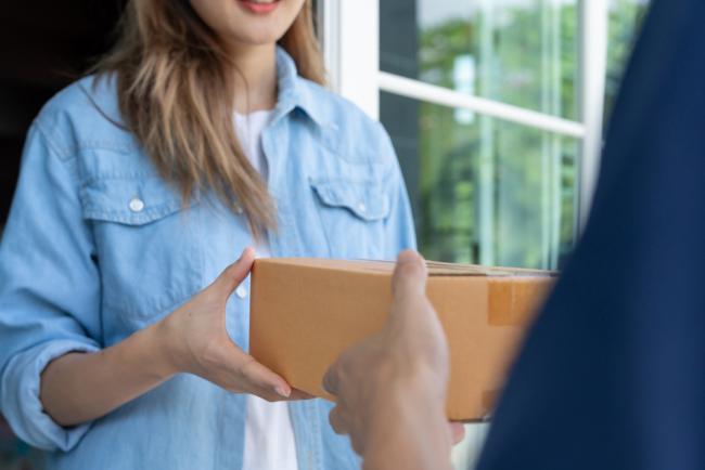 Woman accepts a small package from a delivery person.