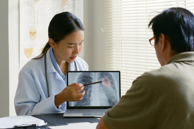 Doctor showing lung x-ray test results to a patient in a hospital.