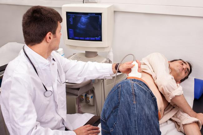 Photo of a medical technician giving a man a sonogram.