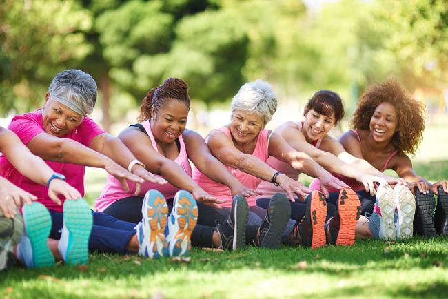 Group of women doing yoga stretches in a park.