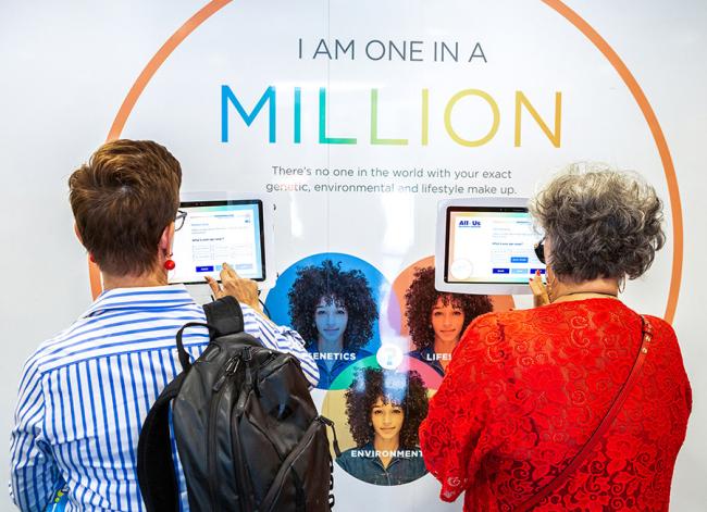 two people interacting with an 'I AM ONE IN A MILLION' interactive display